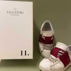 Valentino Garavani sneakers - Snygga Valentino open skor med en röd färg. Skick 7/10 pågrund av att undersulan har visst slitage. Och att några få stygn har lossnat. Det är ett par stilrena skor som ger en skön look. Det är storlek 41 men passar även 42