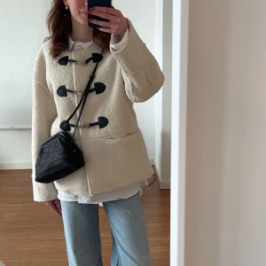 Beige teddyjacka med knäppning - Säljer en mysig beige teddyjacka med unik knäppning framtill. Jackan har långa ärmar och en avslappnad passform, perfekt för kyligare dagar. Den är både stilren och bekväm, ett måste i garderoben! 🧥✨storlek xs/s. Köptes för 1400 på mq förra hösten. Använd fåtalgånger, nyskick.💖