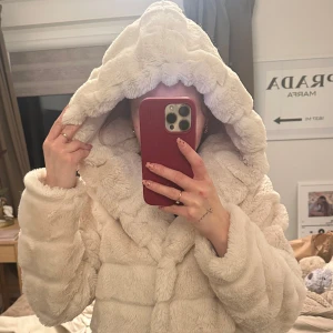 Vit pälsjacka från SNK Paris - Säljer en supermjuk och fluffig vit pälsjacka från SNK Paris. Jackan har en stor huva och stängs med knappar framtill. Perfekt för att hålla sig varm och stilren under kyliga dagar. 🐻✨Har fickor!! Storlek M (är själv petite och är XS) men passar super till olika kroppar.