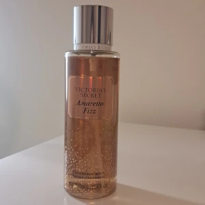 Amaretto Fizz ,Victoria's Secret, body mist. - En lyxig doftmist från Victoria's Secret med namnet Amaretto Fizz. Flaskan är genomskinlig med en elegant silverfärgad kork och rymmer 250 ml. Doften har inslag av mandelkaffe och apelsinblomma, vilket ger en söt och fräsch känsla. Använt 1 spray bara.