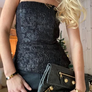 Svart tubtopp med glittrig yta - Snygg fest topp från HM. Köpt från Plick. Toppen säljs inte längre💗