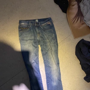 Blå jeans från Replay - Snygga blå jeans från Replay med klassisk femficksdesign och broderade detaljer på bakfickorna. De har en normal passform och är perfekta för en avslappnad stil. Märkeslappen i läder baktill ger en extra touch.