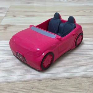 Liten leksaksbil  - Det är en rosa liten bil för småleksaker, stor plats inuti, det finns klistermärken framför och bakom där det står Barbie. 