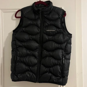 Peak performance väst - Säljer en svart dunväst från Peak Performance med dragkedja och broderad logga på bröstet. Västen har en quiltad design och är perfekt för kyligare dagar. Två praktiska fickor med dragkedja på sidorna. Storlek 160, men passar XS-S. Pris kan diskuteras💞