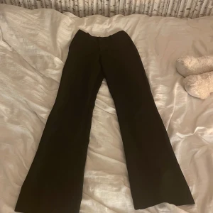 Svarta kostymbyxor  - Snygga svarta byxor. Perfekta för en stilren look. Byxorna har en hög midja och är tillverkade i ett mjukt material som ger en bekväm passform. Säljes pågrund av förstora. Nypris är 499kr💕om frågor tveka inte att höra av er 