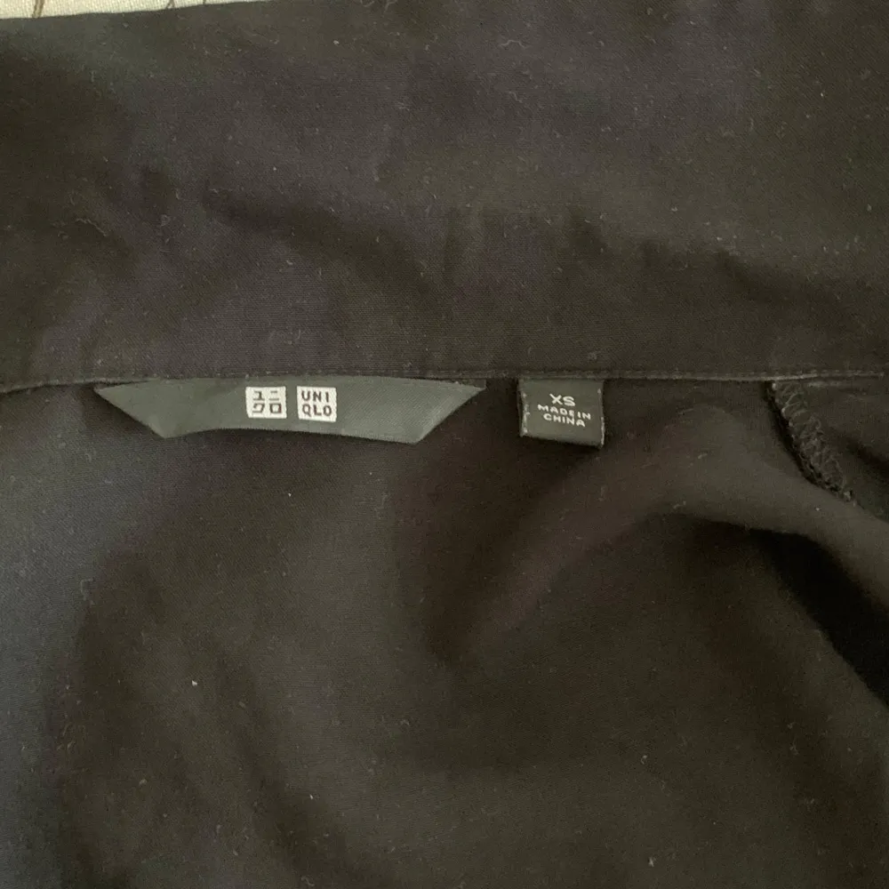 stilren svart skjorta från Uniqlo. Skjortan har långa ärmar och knappar framtill.. Paidat.