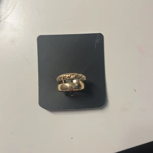 Guldfärgade ringar - Två stilrena guldfärgade ringar, en med en vriden design och en med en slät yta. Perfekta för att bära tillsammans eller separat för en elegant look.  PRIS KAN ÄNDRAS KOM ME FÖRSLAG!!!