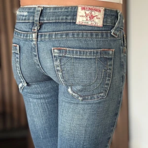 True religion jeans - Lågmidjade bootcut jeans från true religion. Snygg design. Bra skick, se bild. Mått: Innerbenslängd: 81cm   Midjemått rakt över: 36cm Modellen är 166cm lång. Fler bilder finns. Skriv gärna ifall du har några frågor! 💗 OBS se slitningar längst ner vid byxbenens baksidor