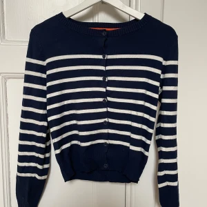 Kofta, randig från Holly & Whyte by Lindex  - Säljer en marinblå kofta med vita ränder. Knappar framtill. 
