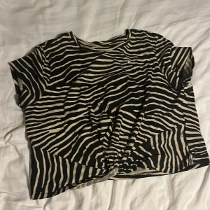 Zebramönstrad kortärmad topp - Säljer en zebramönstrad topp med korta ärmar. Toppen har en knutdetalj framtill och ganska kort mage🤎
