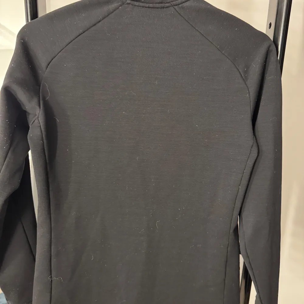 Snygg svart jacka från Peak Performance med dragkedja framtill och två praktiska fickor med dragkedjor. Jackan har en stilren design och är perfekt för kyligare dagar. Den är långärmad och har en hög krage för extra värme.. Takit.