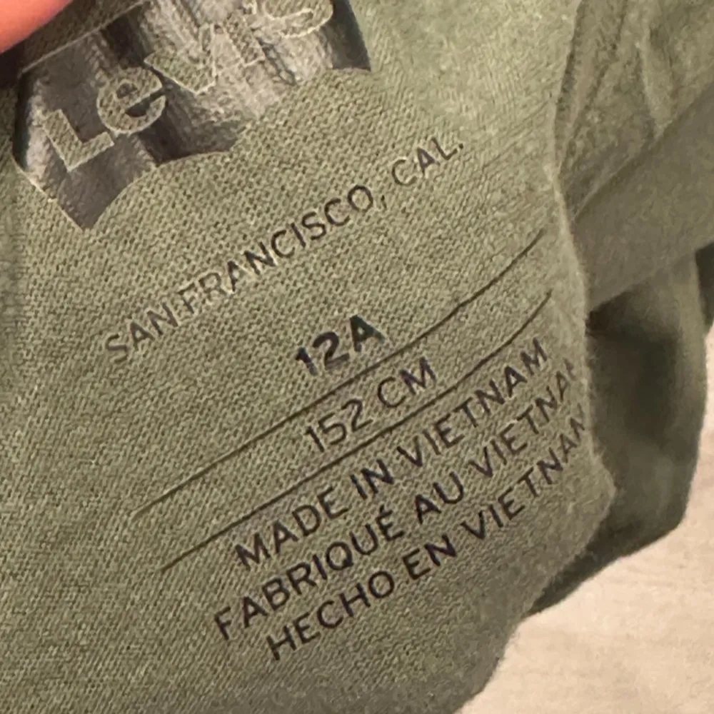 Säljer en grön långärmad tröja från Levi's med tryckt logotyp på bröstet. Perfekt för en avslappnad stil. Tröjan är tillverkad i mjukt material och har en rund halsringning.. Neuletakit & Villapaidat.
