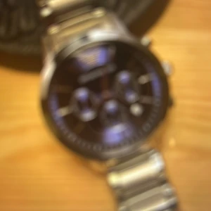 Silverfärgad klocka med länkarmband - Snygg klocka med silverfärgat länkarmband och mörk urtavla. Klockan har flera sub-dials och en klassisk design som passar till många tillfällen.