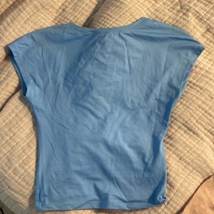 Blå topp från BikBok - Säljer en snygg blå topp från BikBok i storlek XS. Toppen har en urringning och korta ärmar, perfekt för sommaren! Endast andvänd ett fåtal gånger och är så gott som ny!