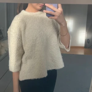 Beige fluffig tröja - Mysig beige tröja med en fluffig textur. Tröjan har trekvartsärmar och en lös passform, perfekt för kyligare dagar. Enkel och stilren design som passar till många olika outfits.
