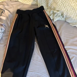 Axel Arigato bee bird track pants  - Snygga svarta bee bird track pants från Axel Arigato med elastisk midja och färgglada ränder längs sidorna. Byxorna har en broderad fågel på ena benet. Perfekta för en avslappnad stil. Knappt använda, i mycket bra skick. Storlek XS men är stora i storleken, är egentligen storlek s/m, är 175, 85kg o de sitter bra på mig!