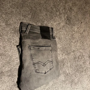 Grå Replay anbass jeans - Snygga grå jeans från Replay Hyperflex med en klassisk femficksdesign. De har en normal passform och är tillverkade i ett stretchigt material för extra komfort. Perfekta för en stilren look. Storlek 30,30 