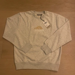 Helt ny Grå sweatshirt från Carhartt - Säljer en snygg grå sweatshirt från Carhartt som finns i storlek XS, S, M och L . Tröjan är helt ny med etikett kvar. Kommer inplastad i orginalförpackning. Den har ett broderat Carhartt-märke på bröstet och 'Detroit' broderat på ärmen. Perfekt för en avslappnad stil! Super schysst nu till hösten och vintern! Det är bara att skriva vid funderingar!