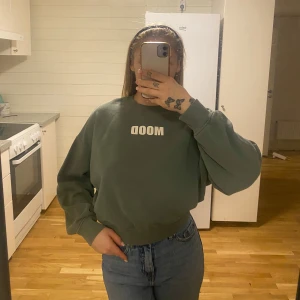 Grön sweatshirt från BIKBOK - Säljer en grön sweatshirt från BIKBOK i storlek M. Den har texten 'MOOD' tryckt på framsidan. Perfekt för en avslappnad stil och passar bra till jeans. Tröjan är i bra skick och superbekväm att ha på sig. Perfekt för höst och vår!