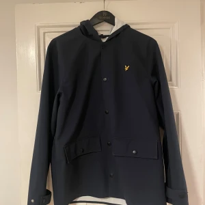 Mörkblå Lyle & Scott jacka - Lyle and scott jacka. Aldrig använd. Funkar under regniga som soliga dagar med en bra luva. Pris kan diskuteras vid snabb affär! 