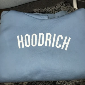 Blå hoodie från Hoodrich - Säljer en snygg blå hoodie från Hoodrich i bra skick. Den har en stor ficka fram och justerbar huva med snören. Den har även en ficka i armen. Den är helt ny. Jag är 164 och den sitter lite oversized 