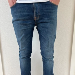 Blå jeans från Nudie Jeans - Säljer ett par snygga blå jeans från Nudie Jeans i storlek 31/32. De har en slim passform och är i mycket bra skick. Perfekta för både vardag och fest! 🕺