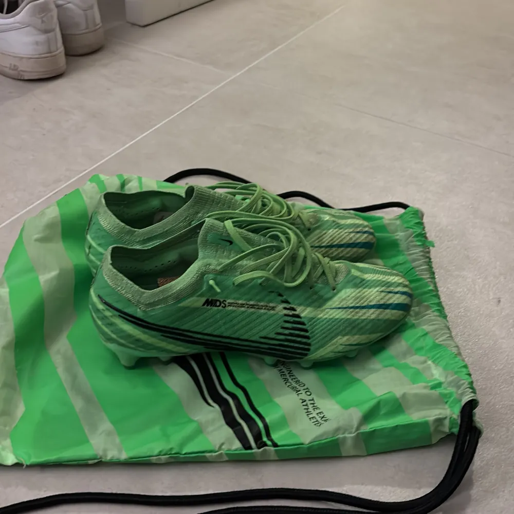 Säljer ett par grymma gröna fotbollsskor från Nike. De har en cool randig design med snörning och är i mycket bra skick. Perfekta för fotbollsträning eller match! Sulan har Zoom-teknologi för extra komfort och grepp. Köpta för 3300kr i mars, använda men finns en säsong eller två kvar;). Skor.