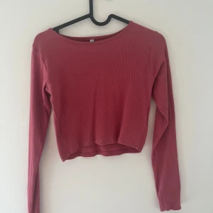 Lila ribbad tröja - Säljer en snygg röd ribbad tröja med långa ärmar och cropad stil. Tröjan är i bra skick och passar perfekt till höstgarderoben. Skön och stilren design som funkar till det mesta!