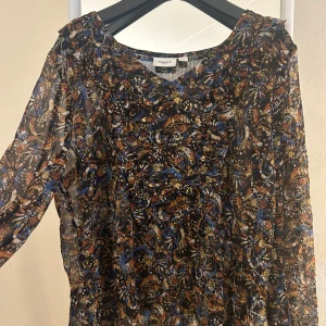 Mönstrad blus från Saint Tropez - Säljer en färgglad mönstrad blus från Saint Tropez i storlek S. Perfekt för både vardag och festliga tillfällen. Den har långa ärmar och en bekväm passform.