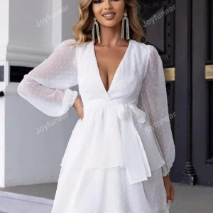 Vit klänning med knyt och volang - Superfin vit klänning med v-ringning och knyt i midjan. Den har långa ärmar och ett diskret prickigt mönster. Perfekt för sommarens fester, studenten eller midsommarfirandet! 💫