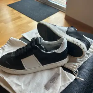 Säljer ett par snygga svartvita Valentino sneakers i mycket bra skick. De har en stilren design med svarta snören och vita detaljer. Perfekta för både vardag och fest! Kommer med originalpåse. Alla nitar kvar. de är 40,5 men de passar 1 storlek större så upp till 42 ungefär så jag skrev storlek 41