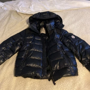 Svart dunjacka från Moncler - Säljer en snygg svart dunjacka från Moncler. Köpt här på plick och hade en liten reva som lagades som man kan se på bild 5. Dragkedjan är också lite sliten.  Är en skidjacka och funkar perfekt för skidresor när det är kallt ute! Pris kan diskuteras 💖