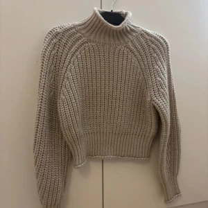 Beige stickad polotröja - Säljer en supermysig beige stickad polotröja. Hög krage och långa ärmar. Tröjan är croppad och med tjock textur som håller än varm. Använd endast en gång, därav mycket bra skick!!