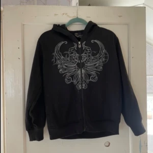 Svart hoodie med mönster - Säljer en svart hoodie från Zy4wz med ett coolt, detaljerat mönster på framsidan. Den har en dragkedja och långa ärmar, perfekt för en avslappnad stil. Passar bra till både vardag och chillkvällar. 🖤