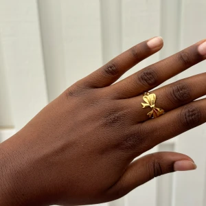 Charmig Guld Rosett Ring - Guldfärgad rosettring, tillverkad i rostfritt stål och justerbar för perfekt passform.