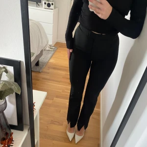 Svarta kostymbyxor - Säljer ett par stilrena svarta kostymbyxor. De är högmidjade och har en slim passform som ger en snygg siluett. Perfekta för både kontoret och festligare tillfällen. Byxorna är i nyskick och har en dragkedja framtill. Säljer då dem är för stora.