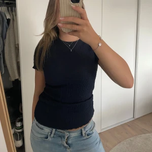 Mörkblå topp med textur - Mörkblå topp i ett popcorn material. Lätt att styla upp till fest/ middag eller styla ner till skolan. Storlek S men materialet är väldigt stretchigt så kan nog passa upp till storlek L