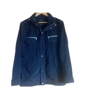 Fieldjacket - Säljer denna feta Fieldjacket från märket riley, jackan är i superfint skick och har en utfällbar luva i kragen för regniga dagar. Storlek 52 motsvarar M/L
