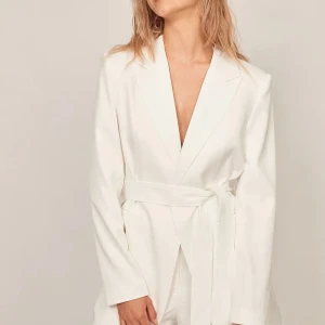 Vit kavaj  - Säljer en elegant vit kavaj med en knappstängning och ett avtagbart skärp. Storlek 36 