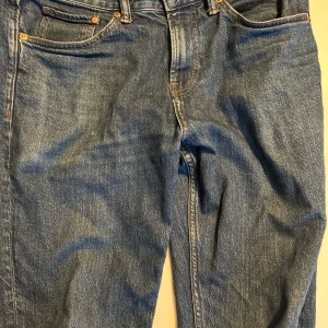 Blå slim fit jeans från H&M - Säljer ett par snygga blå slim fit jeans från H&M. De har en klassisk femficksdesign och är perfekta för både vardag och fest. Jeansen är i bra skick och har en bekväm passform som sitter snyggt på kroppen. Perfekta för dig som vill ha en stilren look!