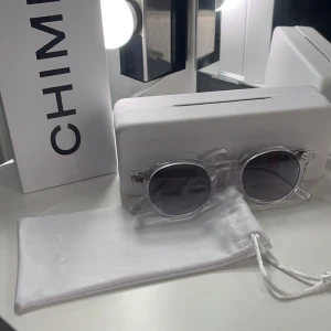 Transparenta solglasögon från Chimi - Säljer ett par snygga solglasögon från Chimi. De har en rund form pga att de är i modell 03, och kommer med ett stilrent fodral och en vit påse för förvaring. Perfekta för att ge din outfit en cool touch! Allt på bild 1 medkommer🔥