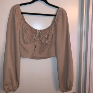 Beige blus med knytning - Säljer en superfin beige blus från Nelly i storlek S. Den har långa ärmar och en söt knytning framtill. Väldigt fint skick! 
