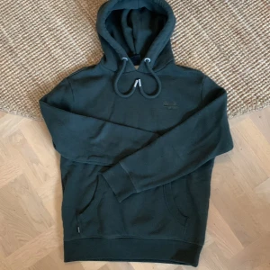 Hoodie Superdry - Tjock fleecad hoodie i storlek M (mer som S). Mörkgrön med ficka framtill. Superskön! Mycket sparsamt använd då den blev för liten.