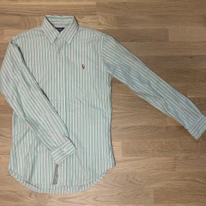Ralph Lauren ”Oxford” Skjorta - En mycket fin ”Oxford” skjorta från Ralph Lauren. Den är i nyskick och dessutom extremt bra kvalitet (100% bomull). Modellen är 183cm och väger 75kg. Vid eventuella funderingar så är det bara att kontakta oss!