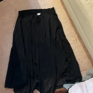 Svart maxikjol från Monki - Lång svart maxikjol från Monki. Midjebandet är ganska stort då den blivit utsträkt. Fick från faster men har aldrig använd själv, säljes därför.