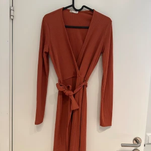 Omlottklänning - En snygg omlottklänning med en fräsch mörk orange färg. 