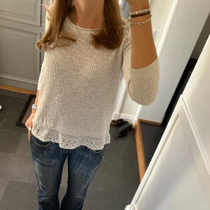 Beige stickad tröja med spets  - Trekvartsärmad beige stickad tröja från Hollister med fastsydd spets längst ner (sista bilden). Fint skick. Storlek M, passar även S. Använd gärna köp nu!