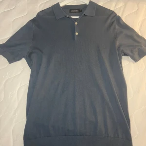 Blå pikétröja från Dressmann - Säljer en stilren blå pikétröja från Dressmann i storlek L. Aldrig använd pga fel storlek. Perfekt för både vardag och lite finare tillfällen. Materialet är mjukt och bekvämt. Passar bra till jeans eller chinos!