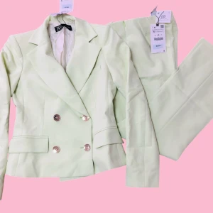 Ljusgrön kavaj och byxor från Zara - Snygg mycket ljusgrön kostym från Zara i storlek S. Kavajen har en dubbelknäppt design med stiliga knappar och byxorna är raka och eleganta. Perfekt för vårens och sommarens fester eller en chic dag på jobbet. Nytt skick med prislapp kvar. Ordinarie pris runt 1000 kronor. Består av en blazer i storlek S och byxor i storlek M, men de passar mer som en S. 