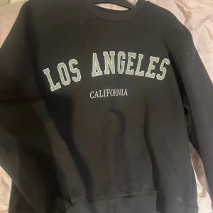 Svart sweatshirt från Gina Tricot - Säljer en svart sweatshirt från Gina Tricot med texten 'Los Angeles California' tryckt på framsidan. 